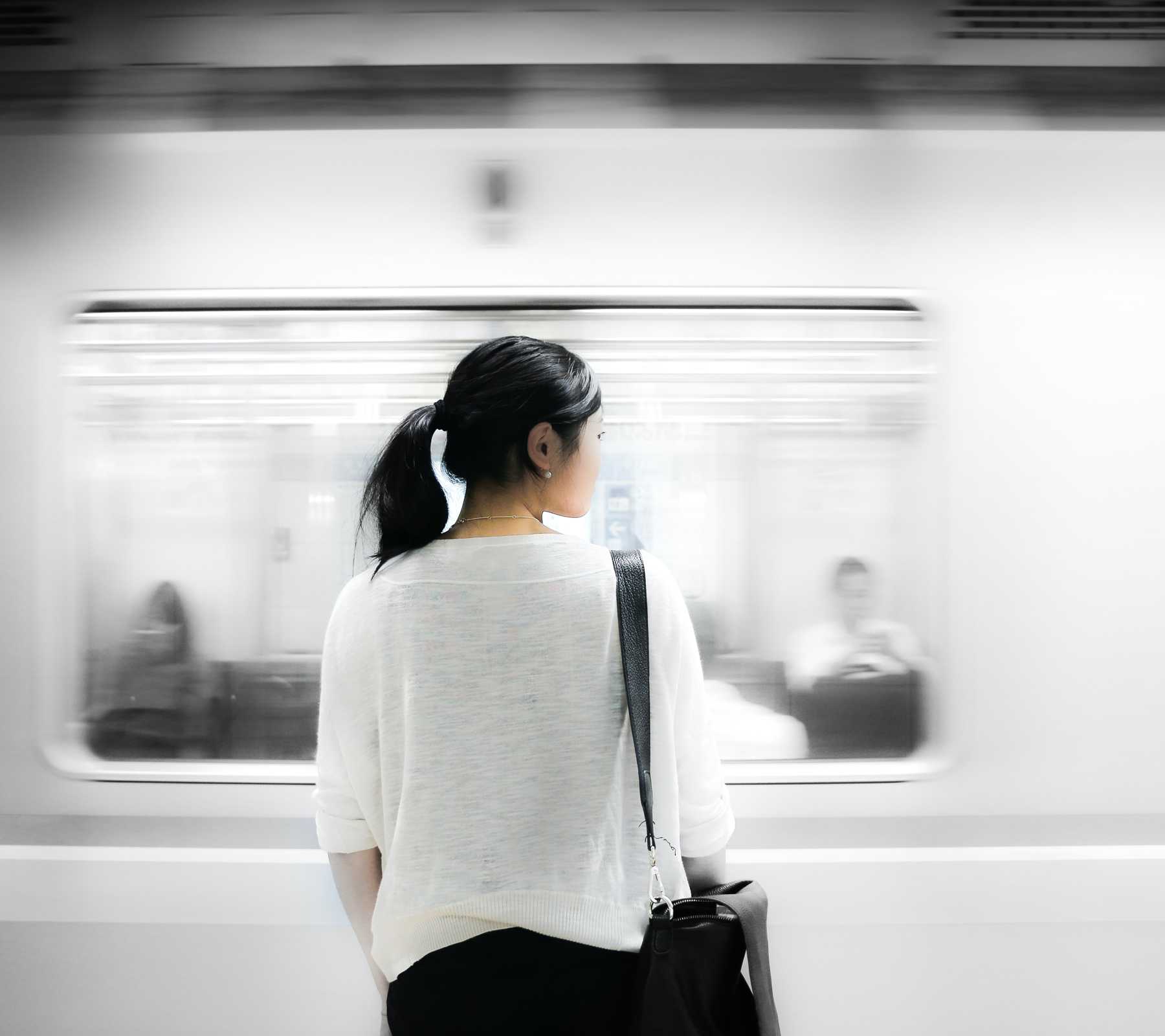Train passing an Asian women on platform.