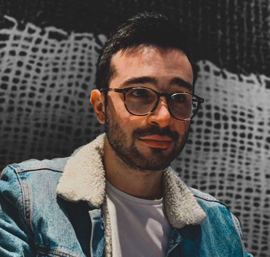 A young man with glasses and a beard looks on the verge of tears.