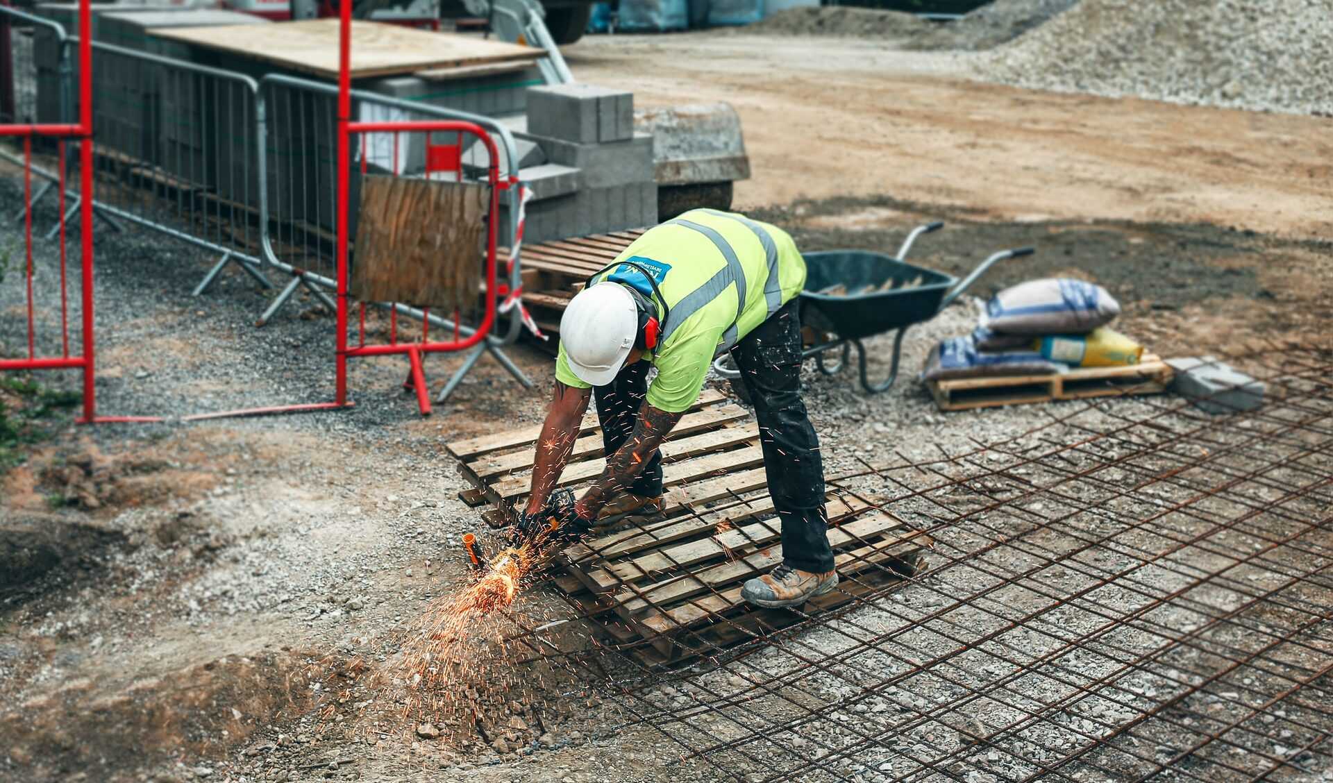A labourer dressed in high vis clothing using a steel saw