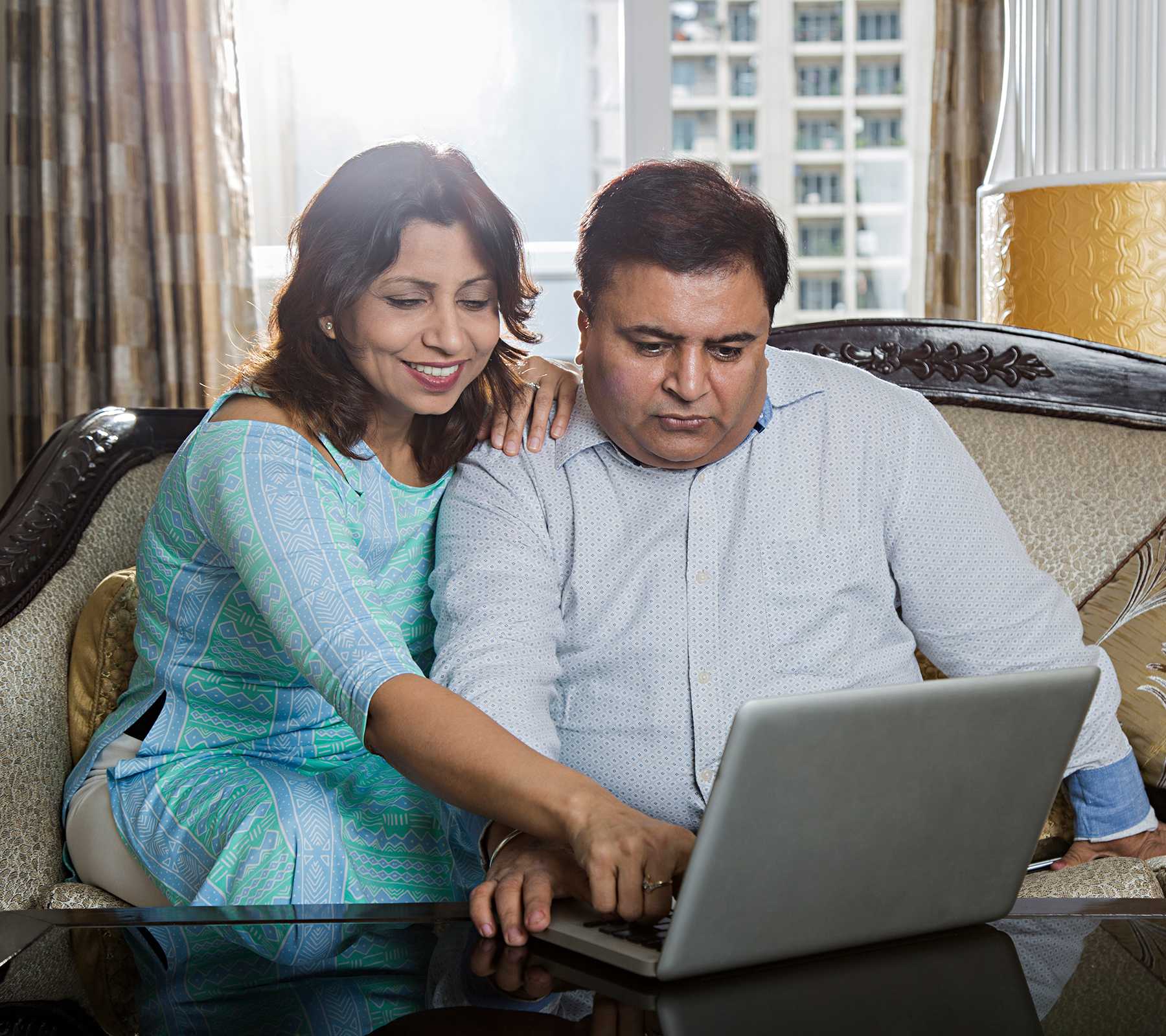 Asian/Indian woman and man looking at a laptop screen. The women points at something on the screen.