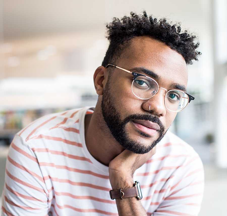 A young black man with glasses stares at the camera
