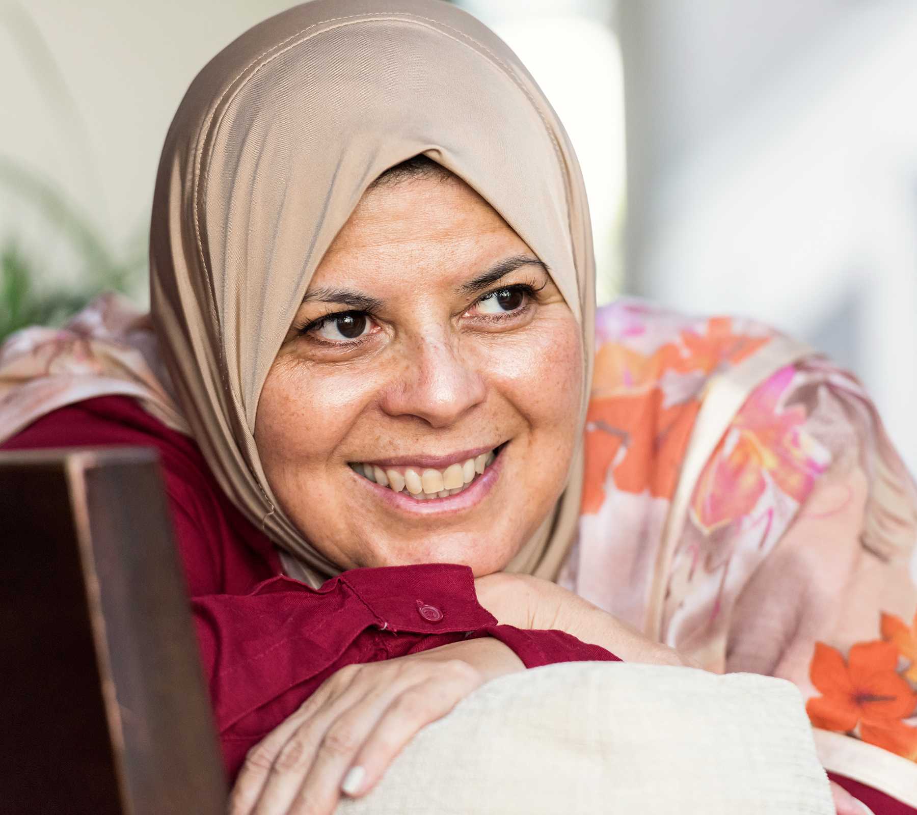 Close up picture of a smiling mature Middle Eastern Muslim woman wearing a veil posing indoors.