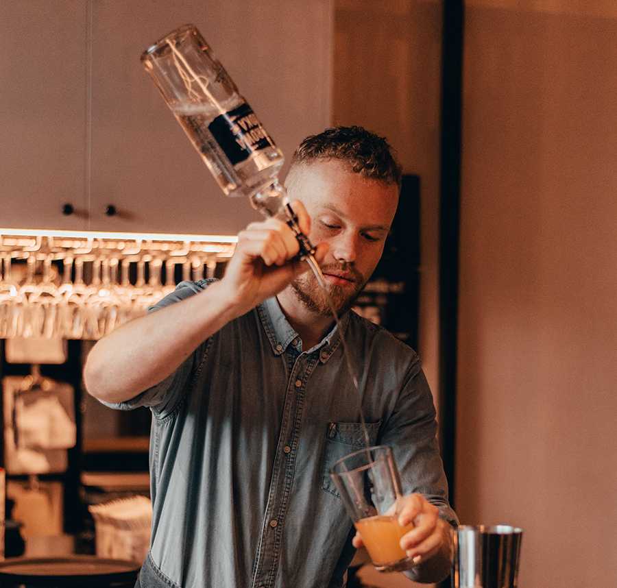 A bartender pours a drink behind the bar.
