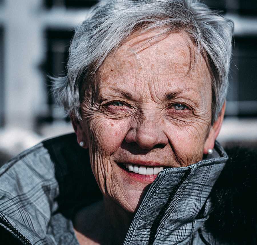 A grey haired older lady smiles at the camera